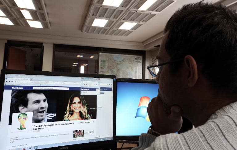 An Iranian man looks at a Facebook page bearing portraits of Argentinian football star Lionel Messi and Brazilian model Fernanda Lima, a presenter at the World Cup draw, at his office in Tehran on December 9, 2013