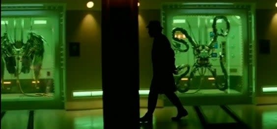 The Gentleman walking down a hall with Doctor Octopus's tentacles and Vulture's wings on display in "The Amazing Spider-Man 2"