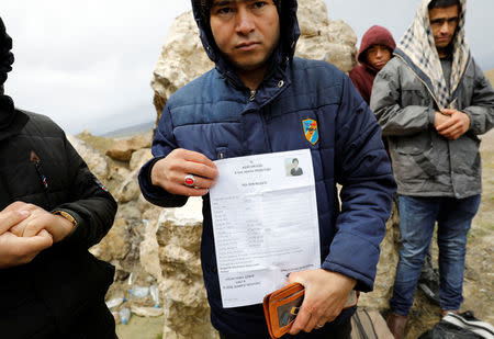 An Afghan migrant shows a travel document during a break from his walk on a main road after crossing the Turkey-Iran border near Dogubayazit, Agri province, eastern Turkey, April 11, 2018. Picture taken April 11, 2018. REUTERS/Umit Bektas