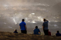 Residents look from a hill as the lava from a volcano eruption flows on the island of La Palma in the Canaries, Spain, Friday, Sept. 24, 2021. A volcano on a small Spanish island in the Atlantic Ocean erupted on Sunday, forcing the evacuation of thousands of people. Experts say the volcanic eruption and its aftermath on a Spanish island could last for up to 84 days. (AP Photo/Emilio Morenatti)