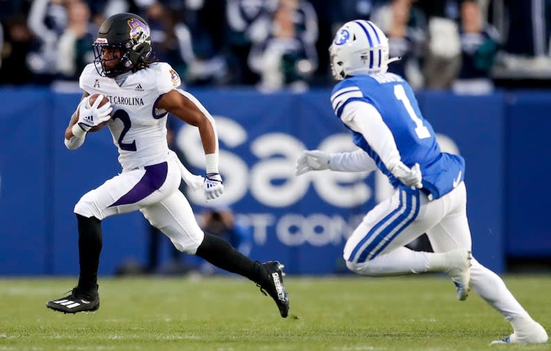 East Carolina Pirates Keaton Mitchell runs the ball while avoiding BYU’s Micah Harper during a game on Oct. 28, 2022, in Provo.