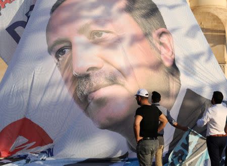 Workers adjust a large election poster of President Tayyip Erdogan in Mardin, capital of Mardin province in southeastern Turkey, June 19, 2018. REUTERS/Goran Tomasevic