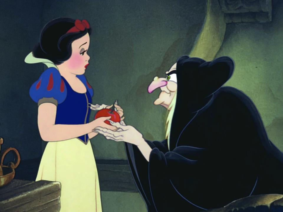 A cartoon scene of a scary witch in a black cloak giving an apple to a scared Snow White.