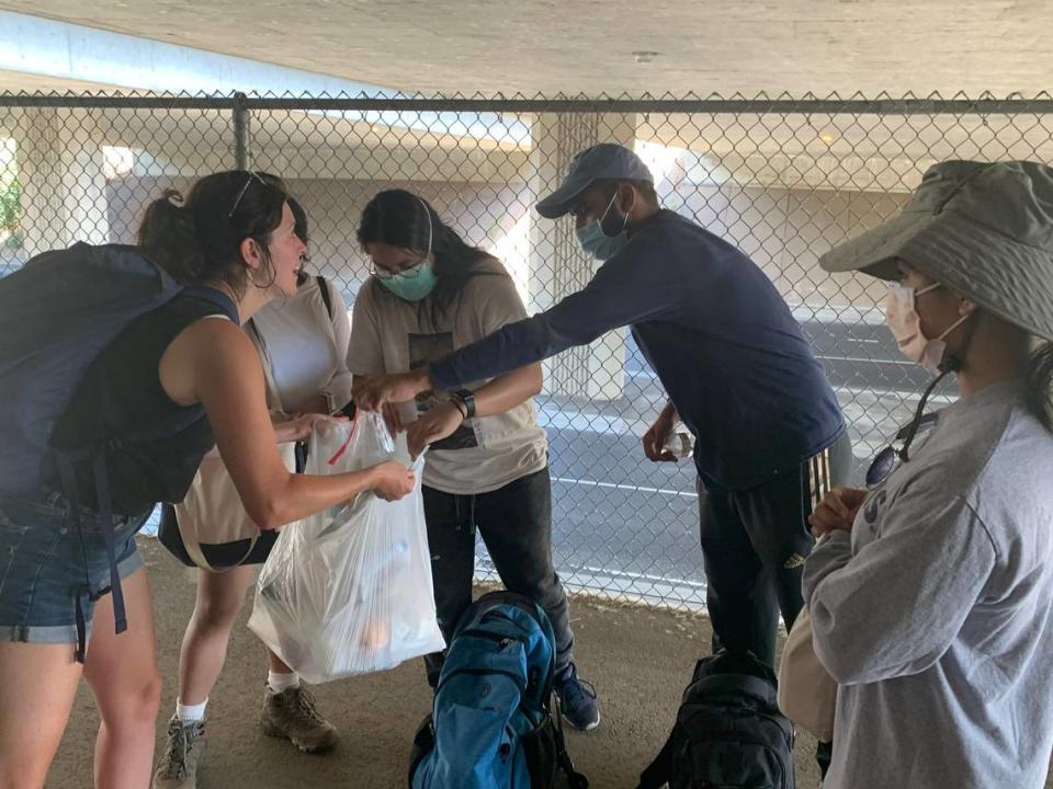 Sacramento Street Medicine member Sam Sears, left, and volunteers organize supply packs for an unhoused community member to distribute around the American River Parkway in Sacramento on July 2.