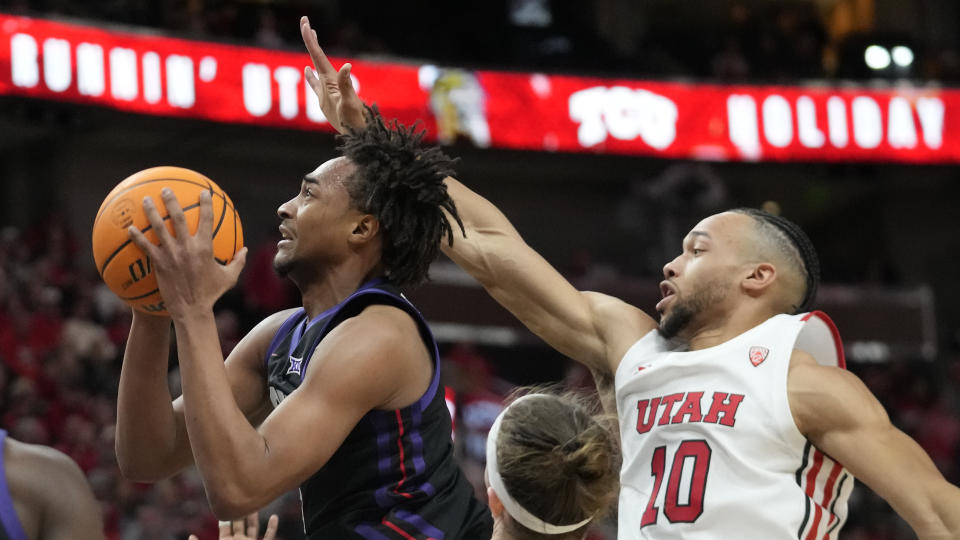 TCU forward Chuck O'Bannon Jr., left, goes to the basket as Utah guard Marco Anthony (10) defends during the first half of an NCAA college basketball game Wednesday, Dec. 21, 2022, in Salt Lake City. (AP Photo/Rick Bowmer)