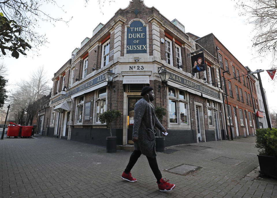 A man walks past the Duke of Sussex pub with a sign depicting the image of Britain's Prince Harry and his wife Meghan, near Waterloo station, London, Tuesday March 9, 2021. Prince Harry and Meghan's explosive TV interview has divided people around the world, rocking an institution that is struggling to modernize with claims of racism and callousness toward a woman struggling with suicidal thoughts. (AP Photo/Frank Augstein)