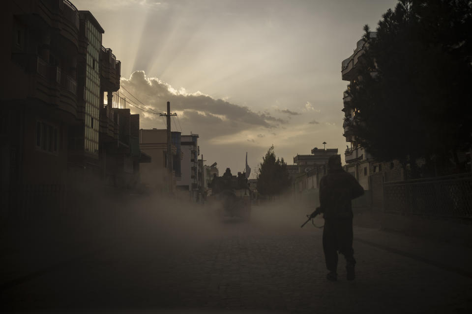 A Taliban fighter walks on the side of a road as a Humvee carrying other fighters drives by in Kabul, Afghanistan, Tuesday, Sept. 21, 2021. (AP Photo/Felipe Dana)