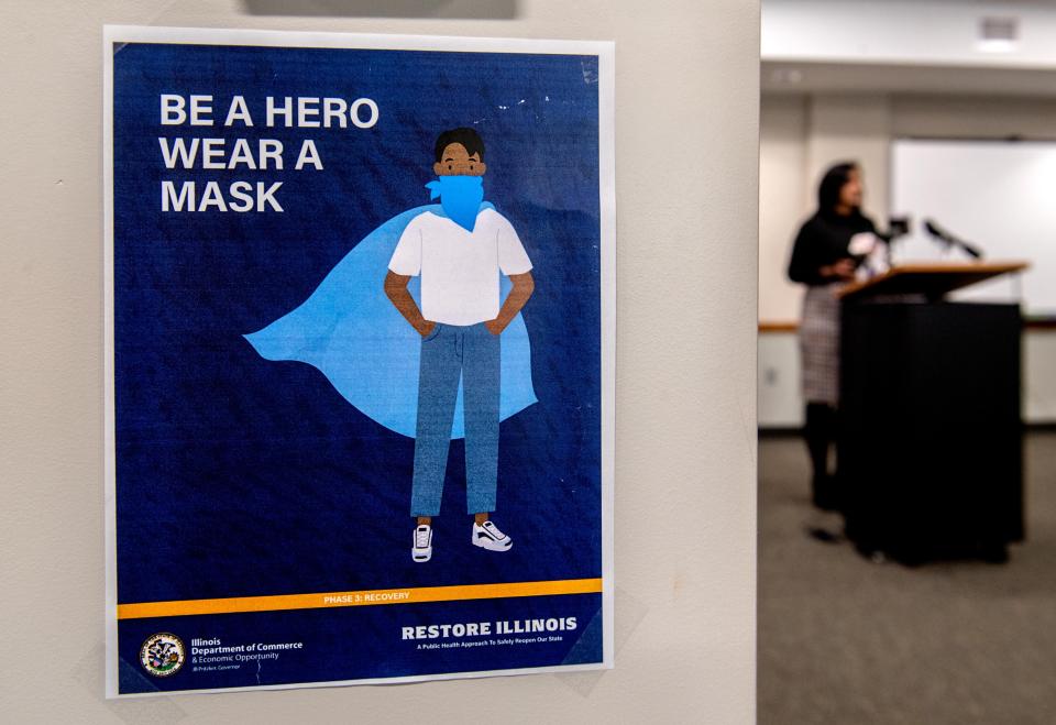 A sign urging residents to wear face masks hangs from a beam as Monica Hendrickson, public health administrator, leads a news conference updating the COVID-19 situation in the Peoria area Thursday, Oct. 1, 2020, at the Peoria City/County Health Department.