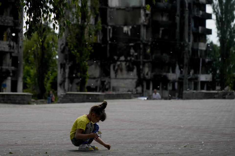 A girl plays at a square near buildings destroyed during attacks in Borodyanka, on the outskirts of Kyiv, Ukraine, Saturday, June 4, 2022. (AP Photo/Natacha Pisarenko)