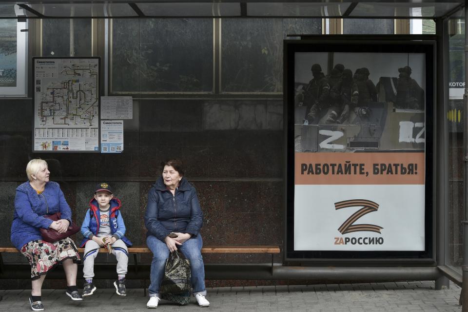 People sit at a bus stop decorated by a letter Z, which has become a symbol of the Russian military in Sevastopol, Crimea, Thursday, May 5, 2022. (AP Photo)