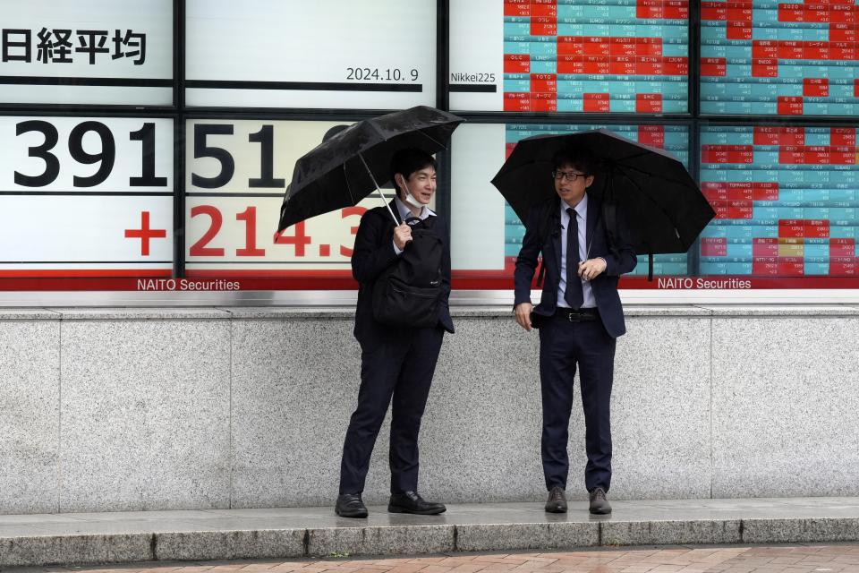 People stand in front of an electronic stock board showing Japan's Nikkei index at a securities firm, Wednesday, Oct. 9, 2024, in Tokyo. (AP Photo/Eugene Hoshiko)