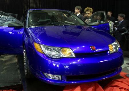 Members of the press look over the new 2003 Saturn ION quad coup at its debut at the New York International Auto Show in New York on March 27, 2002. REUTERS/Peter Morgan