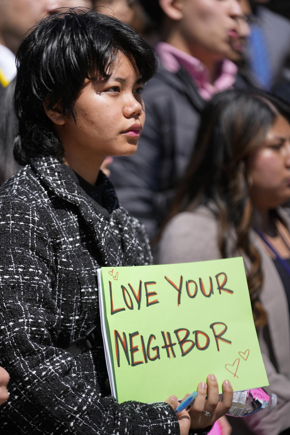 Mary Siam holds a sign during a news conference of the Tennessee Immigrant and Refugee Rights Coalition outside the state Capitol, Tuesday, March 19, 2024, in Nashville, Tenn. Members of the group came to the state Capitol to lobby legislators to vote against legislation that require local law-enforcement agencies to operate as if they have federal 287(g) agreements and a bill criminalizing transportation of undocumented immigrants. (AP Photo/George Walker IV)