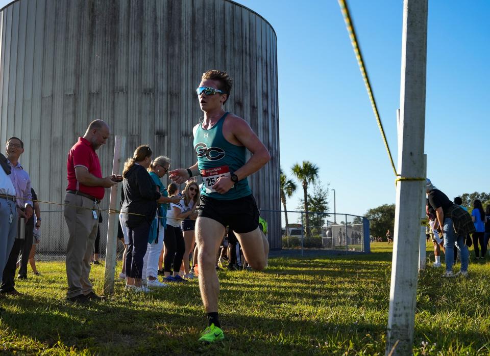 Gulf Coast runner William Montanye crosses the finish line fist while competing in the Collier County Athletic Conference cross country championship at Palmetto Ridge High School in Naples on Wednesday, Oct. 25, 2023.