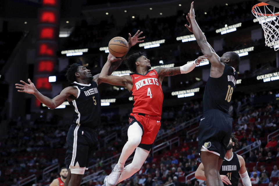 Houston Rockets guard Jalen Green (4) attempts to dunk between Memphis Grizzlies guard Vince Williams Jr. (5) and center Bismack Biyombo (18) during the first half of an NBA basketball game Wednesday, Dec. 13, 2023, in Houston. (AP Photo/Michael Wyke)