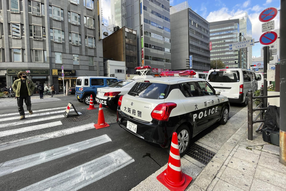 Police cars are pulled up near a building where a fire broke out Friday in Osaka, western Japan, Saturday, Dec. 18, 2021. Japanese police on Saturday searched the house of one of the patients at a mental clinic where the fire gutted an entire floor in the eight-story building, killing over 20 people trapped inside. (AP Photo/Chisato Tanaka)