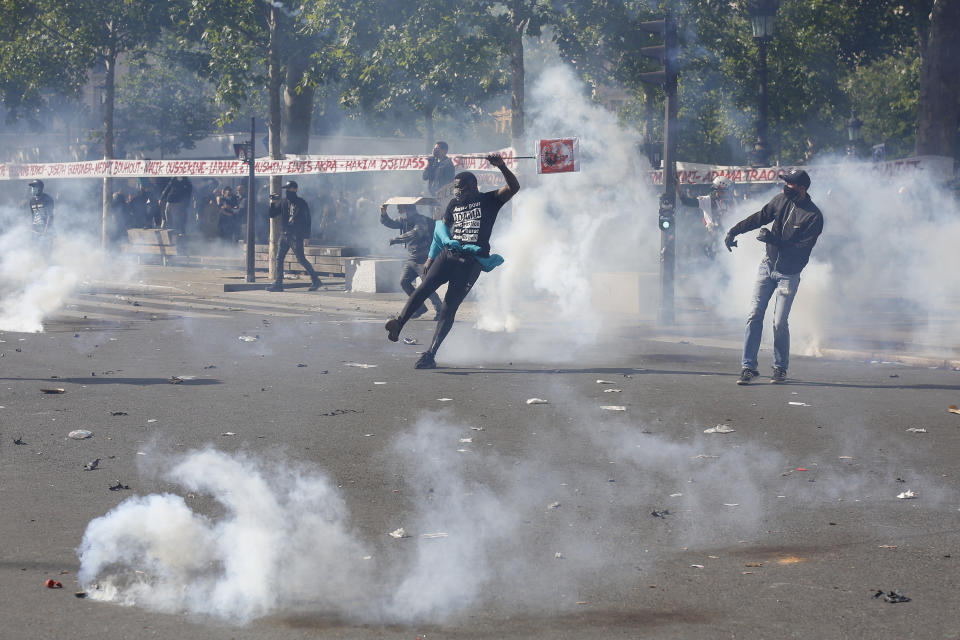 A man kicks a tear gas canister during a march against police brutality and racism in Paris, France, Saturday, June 13, 2020, organized by supporters of Adama Traore, who died in police custody in 2016 in circumstances that remain unclear despite four years of back-and-forth autopsies. The march is expected to be the biggest of several demonstrations Saturday inspired by the Black Lives Matter movement in the U.S., and French police ordered the closure of freshly reopened restaurants and shops along the route fearing possible violence. (AP Photo/Thibault Camus)