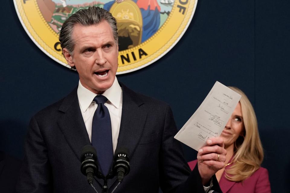 FILE - California Gov. Gavin Newsom displays a bill he signed that shields abortion providers and volunteers in California from civil judgements from out-of-state courts during a news conference in Sacramento, Calif., June 24, 2022.  Newsom is headed to Washington this week, providing him with a national stage to continue his outspoken defense of abortion rights and gun control while lambasting Republican-led states that he sees as a threat to personal freedom and public safety. (AP Photo/Rich Pedroncelli, File)