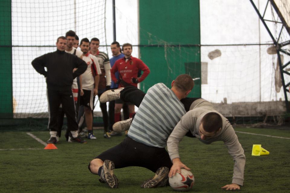 In this photo taken on Sunday, Feb. 2, 2014, members of the Kosovo Roosters Rugby team train on an indoor pitch in Mitrovica, Kosovo. They've been roughing each other up for almost a century without any rules. But, now Serbs and Albanians are tackling a new form to deal with old enmities. Spurred by a group of aid workers they are learning to work together through a sport that is all about gaining territory: rugby. In Mitrovica, a city that has come to symbolize the ethnic split, youths from both side of the divide gather to train and follow instructions from their French, Irish and American trainers. (AP Photo/Visar Kryeziu)