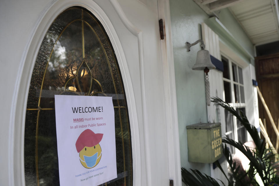 A sign advises guests to wear a face mask at the Island Bay Resort in Tavernier, in the Florida Keys, during the new coronavirus pandemic, Monday, June 1, 2020. The resort is open for guests as the Florida Keys reopened for visitors Monday after the tourist-dependent island chain was closed for more than two months to prevent the spread of the coronavirus. (AP Photo/Lynne Sladky)