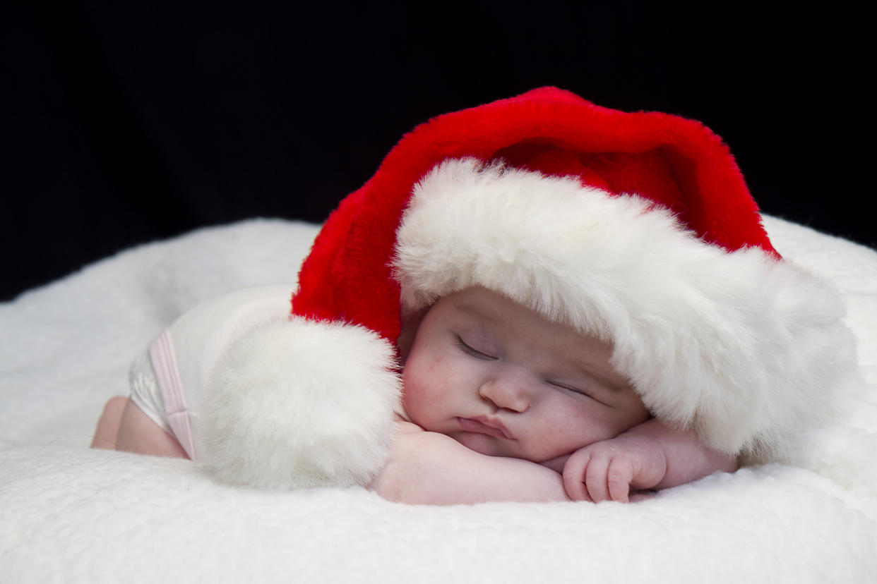 Baby girl wearing red santa hat while sleeping and peeking at times