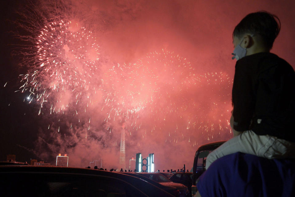 A boy wearing a face mask to help curb the spread of the coronavirus watches fireworks exploded over Pyongyang, North Korea, Monday, July 27, 2020, marking the 67th anniversary of the end of the 1950-53 Korean War. (Kyodo News via AP)