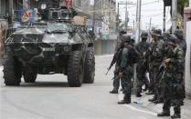 An armoured vehicle drives past government soldiers for another offensive against the Muslim rebels of Moro National Liberation Front (MNLF) positions in Zamboanga city in southern Philippines September 16, 2013. REUTERS/Erik De Castro