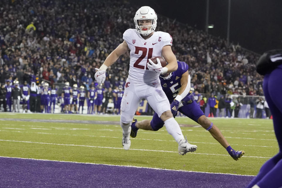 Washington State running back Max Borghi (21) scores a touchdown ahead of Washington defensive back Alex Cook, right during the second half of an NCAA college football game, Friday, Nov. 26, 2021, in Seattle. (AP Photo/Ted S. Warren)