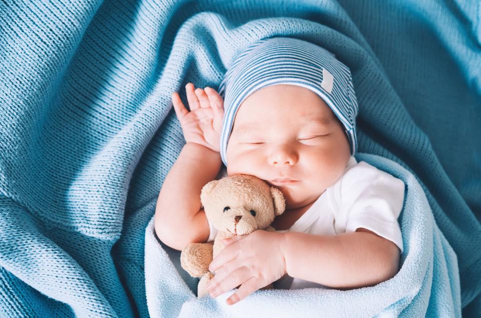 newborn baby sleep at first days of life portrait of new born child boy one week old sleeping peacefully with a cute soft toy in crib in cloth background