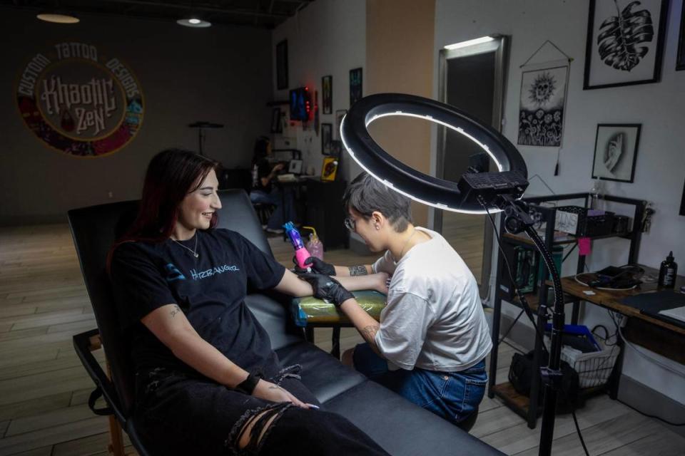 Tattoo artist Bella Harrell works on client Savannah Smith at Khaotic Zen Tattoo in Fort Worth on Thursday, March 23, 2023.