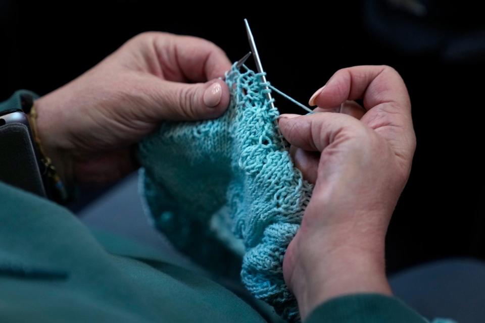 One of the attendees at the Skein Yarn Shop book event knits while listening to author Ann Hood.