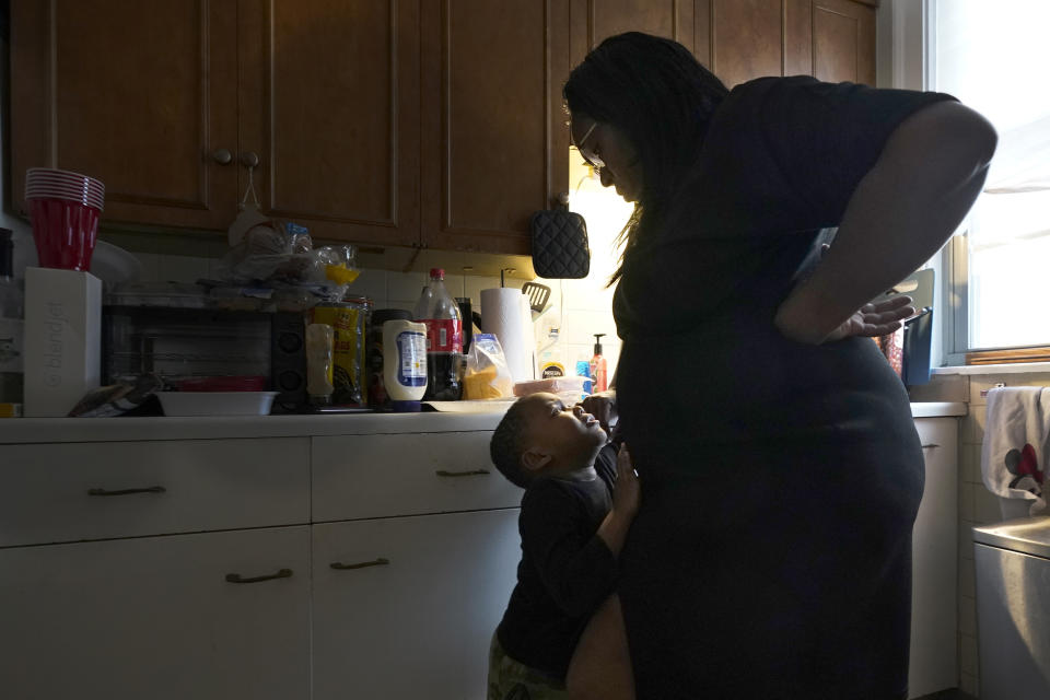 Briana Dominguez, right, listens to her son, Noah Scott, pout about not be able to eat his sandwich on the living room floor instead of at the table, in the kitchen of their Skokie, Ill., apartment on Saturday, Nov. 21, 2020. After her employer eliminated her job, the family is moving to Georgia where living costs are lower. (AP Photo/Charles Rex Arbogast)