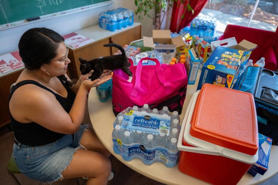 Julia Hernandez, who co-chairs the mutual aid committee at Organize Sacramento, waits with her foster kitten amid an array of water and snacks at a cooling center at 1714 Broadway in Sacramento on Wednesday. The center is open from noon to 8 p.m. during the extreme heat.