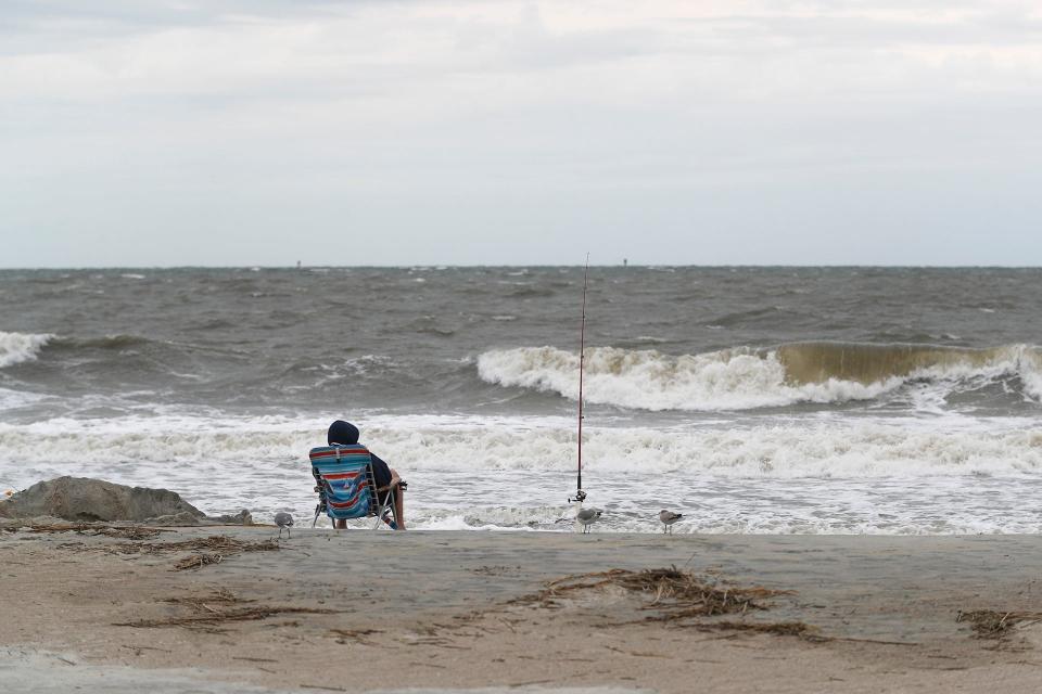 Waves roll to the beach as a fisherman relaxes Wednesday afternoon on Tybee Island.