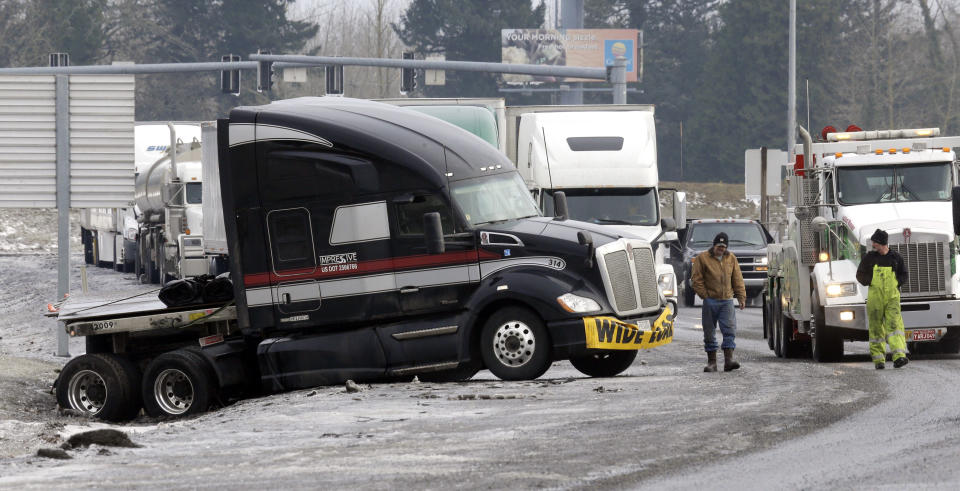 Truck driver Brad Cottle, left, from Florida, surveys the situation with his truck stuck in a ditch with tow truck driver Donny Callahan in Troutdale, Ore., Wednesday, Jan. 18, 2017. An ice storm shut down parts of major highways and interstates Wednesday in Oregon and Washington state and paralyzed the hardest hit towns along the Columbia River Gorge with up to 2 inches of ice coating the ground in some places.(AP Photo/Don Ryan)