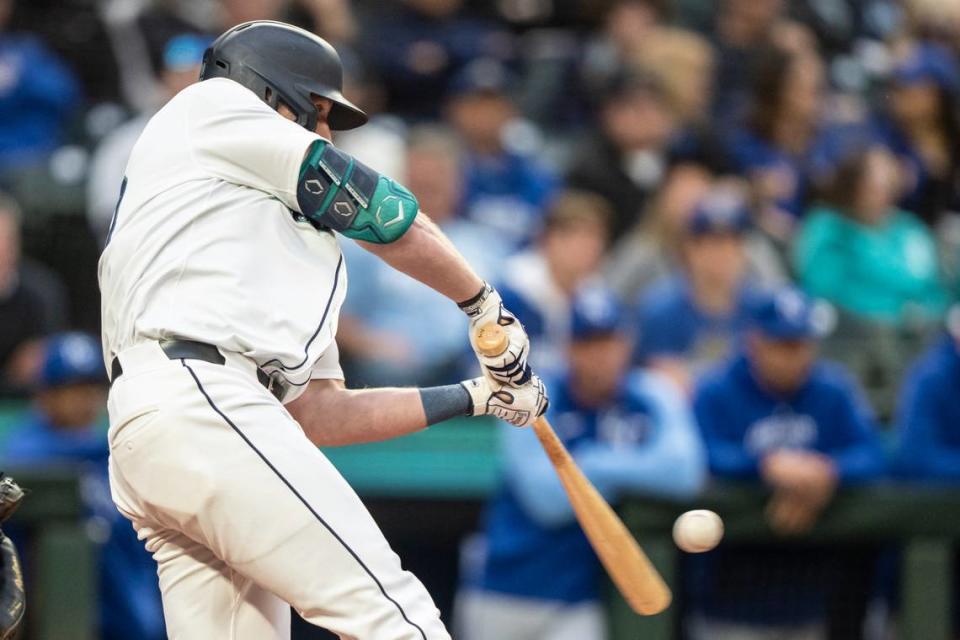 With the Kansas City Royals’ dugout in the background, Mariners left fielder Luke Raley belts a two-run homer during the second inning at T-Mobile Park in Seattle.
