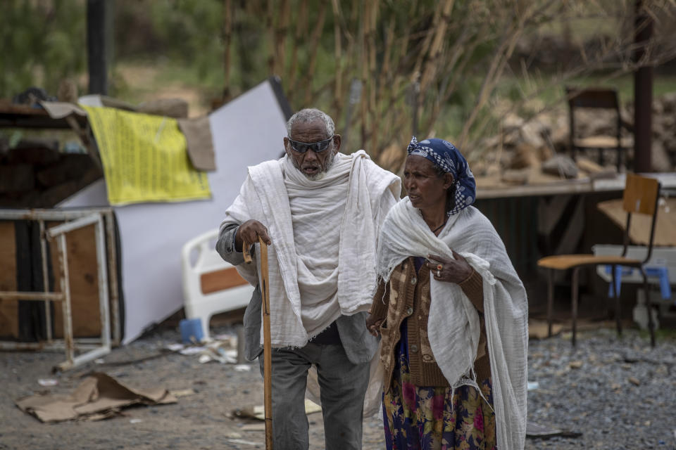 A woman leads a blind man to a visiting doctor, past destroyed furniture and other items in the driveway of a hospital which was damaged and looted by Eritrean soldiers who used it as a base, according to witnesses, in Hawzen, in the Tigray region of northern Ethiopia, on Friday, May 7, 2021. The battle for Hawzen is part of a larger war in Tigray between the Ethiopian government and the Tigrayan rebels that has led to the flight of more than 2 million of the region’s 6 million people. (AP Photo/Ben Curtis)