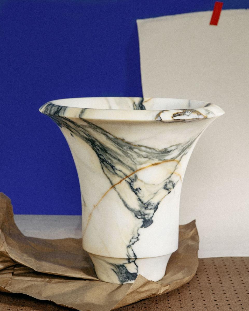 a classical looking white vase with black marbling sitting on a paper bag