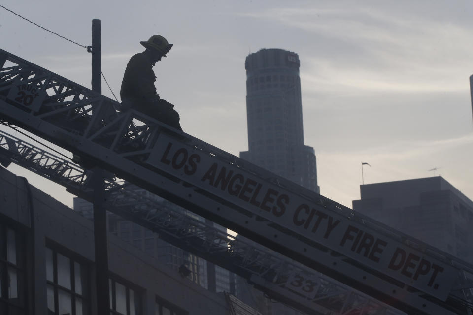 A Los Angeles Fire Department firefighter works the scene of a structure fire that injured multiple firefighters, according to a fire department spokesman, Saturday, May 16, 2020, in Los Angeles. (AP Photo/Damian Dovarganes)