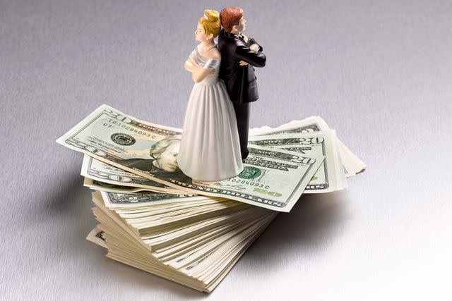 <p>Getty</p> Stock image of wedding figurine couple back to back on a pile of dollars