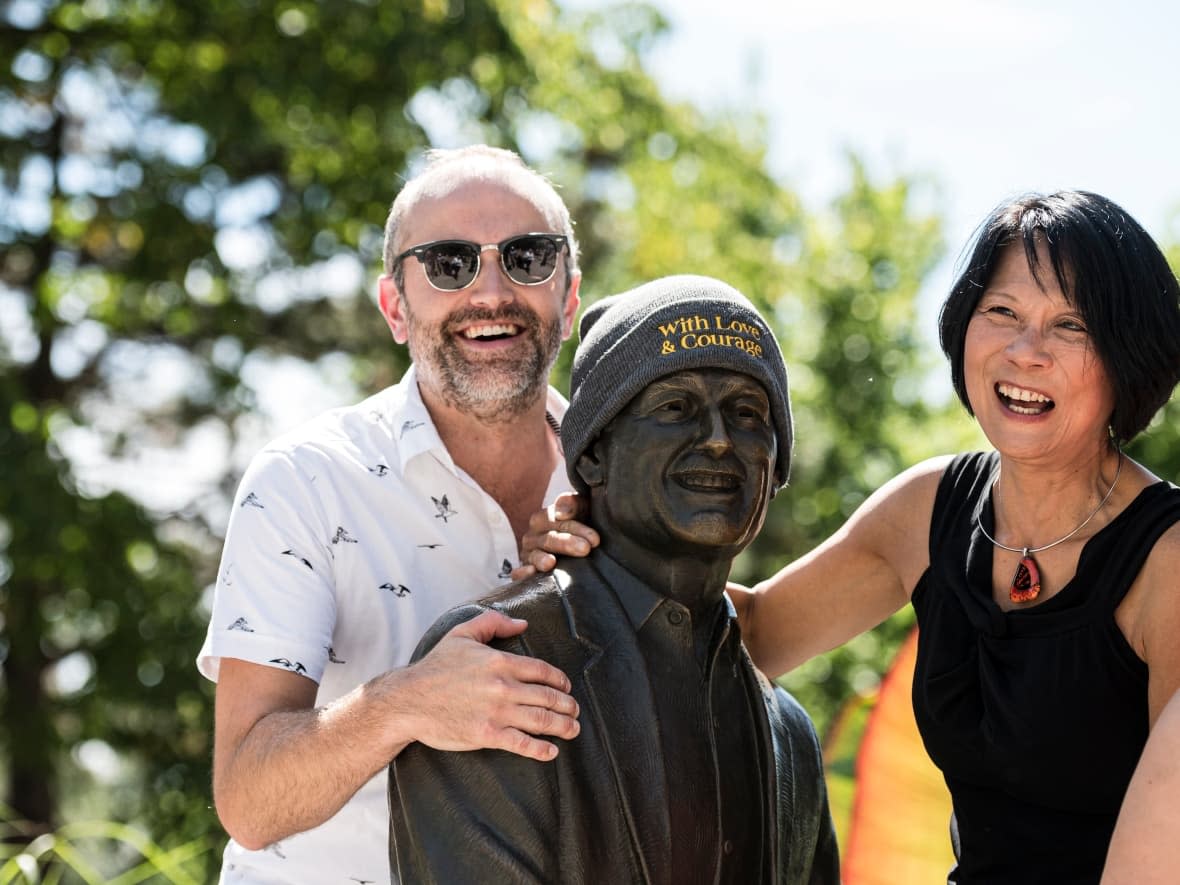 Toronto Coun. Mike Layton, left, and Olivia Chow pose for a photo next to the Jack Layton sculpture by the ferry terminal in 2019. The younger Layton confirmed Wednesday he won't seek re-election in October. (Christopher Katsarov/Canadian Press - image credit)