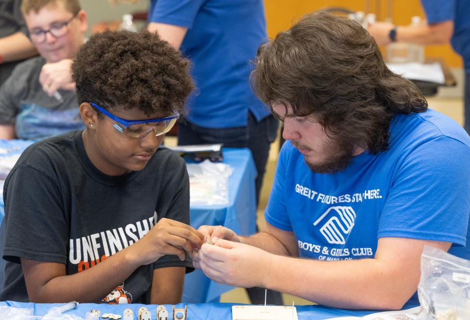 Jesselle Linke, 12, left, receives a hand from Boys & Girls Club of Massillon counselor Isiah McCullough on Tuesday, as they work to construct a replica hydraulic arm during a NASA Astro Camp.