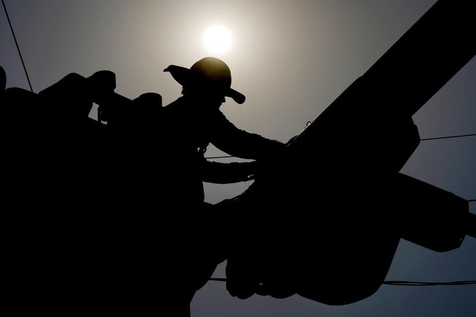 FILE - A linesman works on power lines under the morning sun, July 12, 2024, in Phoenix. (AP Photo/Matt York)