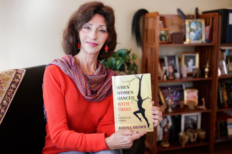 Author of "When Women Danced with Trees," Marina Brown holds her new book featuring 35 short stories for a portrait in her home Wednesday, Oct. 20, 2021.
