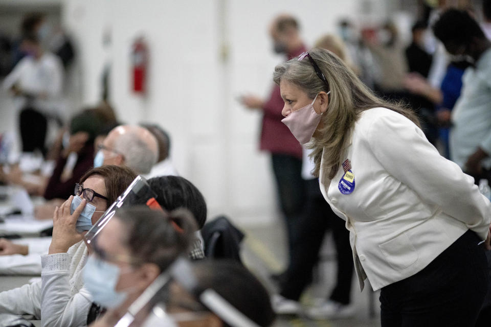 FILE - A Republican election challenger at right watches over election inspectors as they examine a ballot as votes are counted into the early morning hours, Nov. 4, 2020, at the central counting board in Detroit. Election officials across the country are bracing for a wave of confrontations in November as emboldened Republican poll watchers, many embracing former President Donald Trump's conspiracy theories about the 2020 election, flood polling places for the general election. (AP Photo/David Goldman, File)