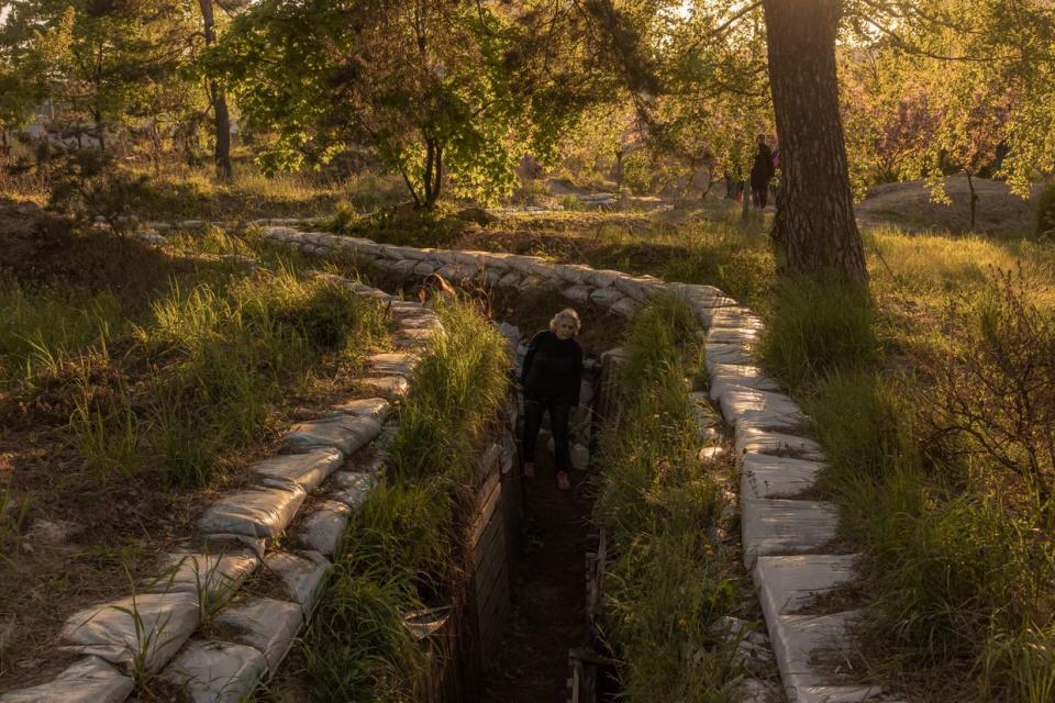 An elderly woman walks through a trench at a park on May 6, 2023, in Kyiv. Parts of the park had been fortified by Ukrainian troops defending the capital at the beginning of the Russian full-scale invasion. Russia launched its assault on Ukraine last year hoping to quickly seize its capital. Instead, its Kyiv offensive met stiff resistance, and by early April 2022, it was forced to withdraw from the region. A year later, the threat of aerial attacks remains in and around Kyiv, but the ground war has largely concentrated in the east and south. (Roman Pilipey/Getty Images)