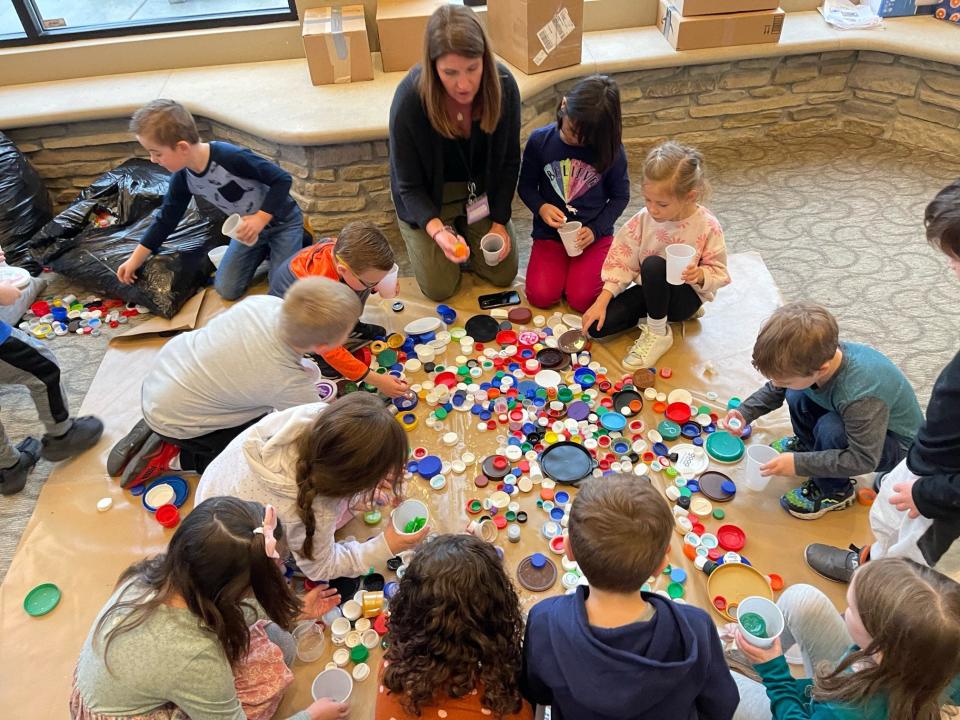 Teacher Krista Daunhauer helps her classroom sort some of the collected plastic caps.