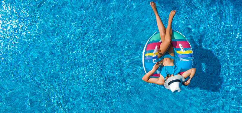 A woman floats on a raft in a swimming pool.