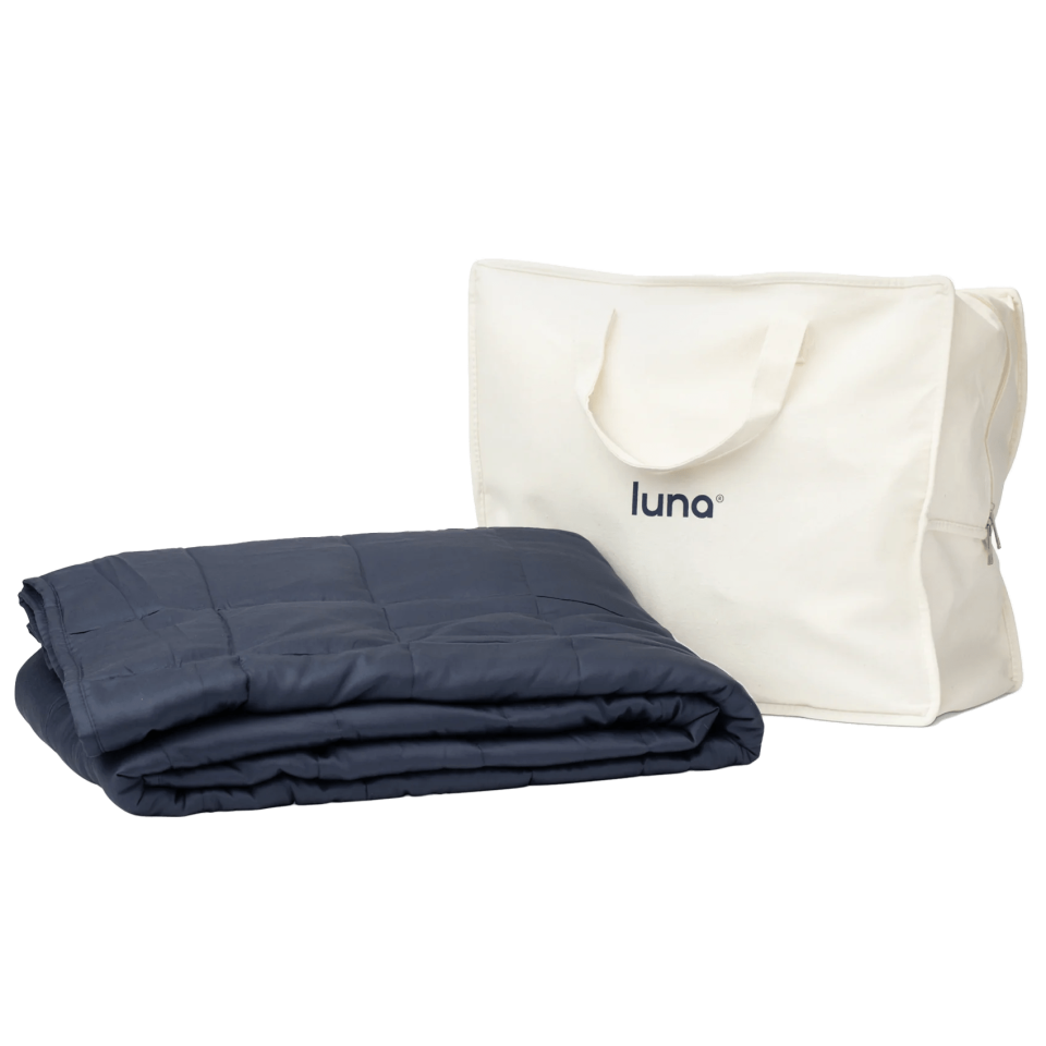 navy blue luna weighted blanket next to white carrying bag