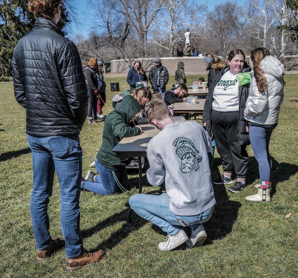 Michigan State students fill write down their thoughts about the Feb. 13 mass shooting on campus that killed three students and wounded five others on a card as part of a Walk Together event Sunday, March 19, 2023. The cards will be archived at the Michigan State Museum and put on display.